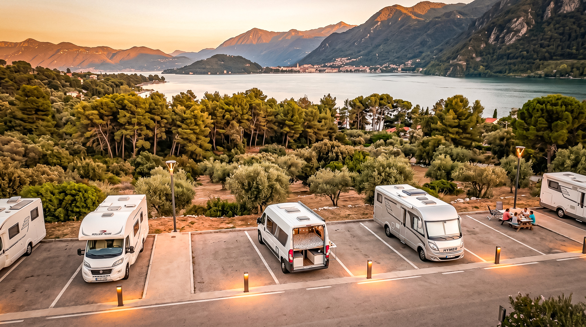 Campervans parked by Lake Como, mountains in the background, sunset.