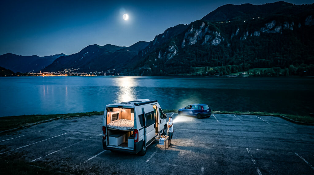 Camper van by Lake Como, Xavier checks the equipment under the moonlight.