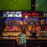 Caroline at the bar of a lively pub in Stirling with screens showing football matches