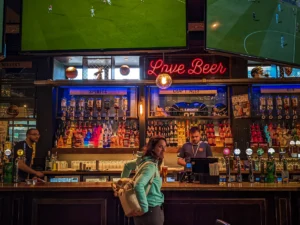 Caroline at the bar of a lively pub in Stirling with screens showing football matches