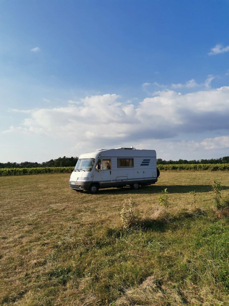 Camper van Edouard is parked in the heart of a meadow under a summer sky, illustrating the freedom of vanlife in nature.