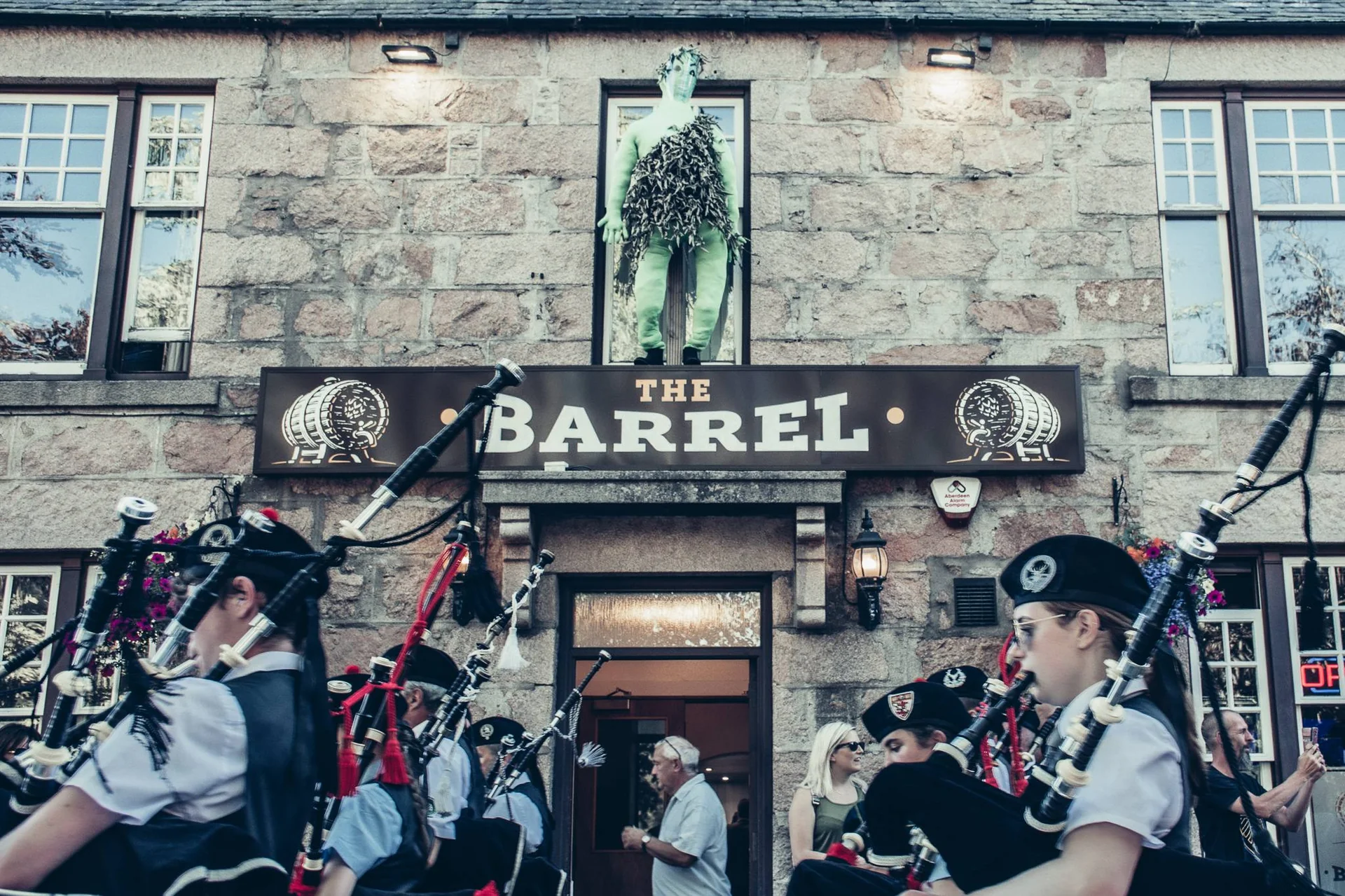 Piper parade in front of a Scottish pub in Ballater during the Highland Games