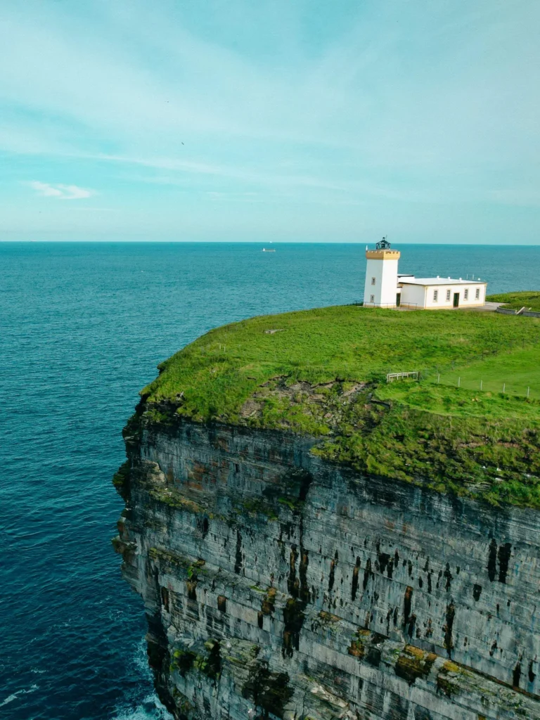 White lighthouse isolated on a cliff overlooking the sea in northern Scotland at John o'Groats