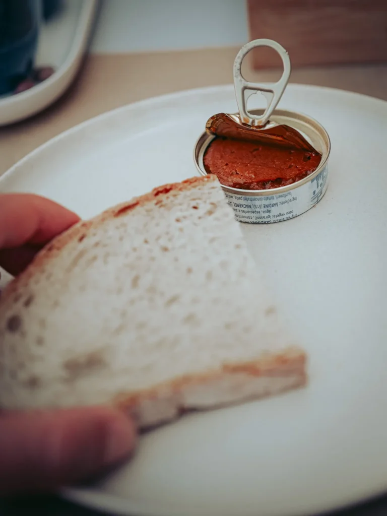 Slice of white bread and a can of artisanal sardine pâté on a plate, served as a starter in a restaurant in Portimao, Algarve.