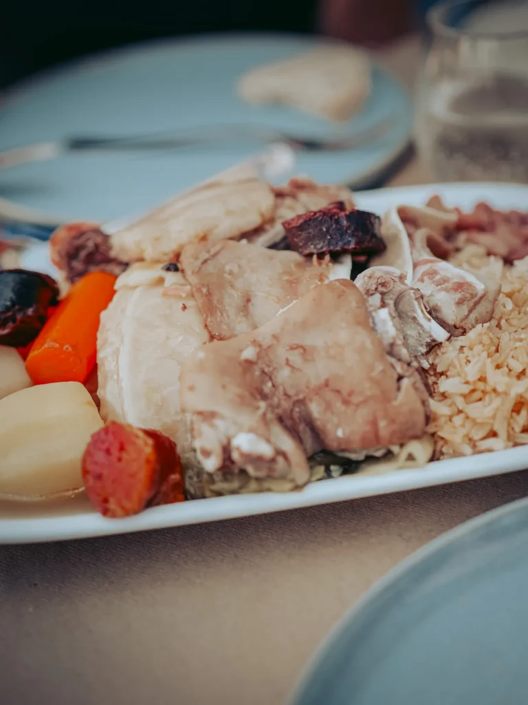 Portuguese cozido served on a plate, with different cuts of meat, vegetables, and rice, on a set table at the O Mané restaurant in Portimão, Algarve.