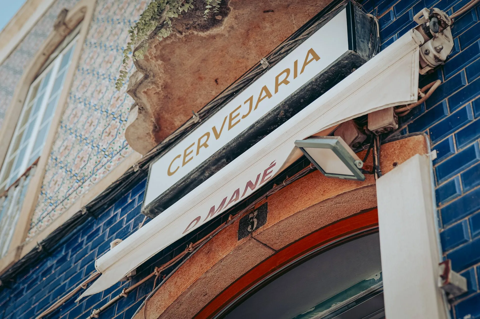 Fassade des Restaurants O Mané in Portimão, Algarve, mit Schild aus dunkelblauen Fliesen.