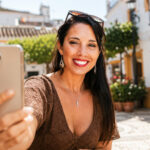 Smiling traveller taking a selfie in a sunny Spanish courtyard