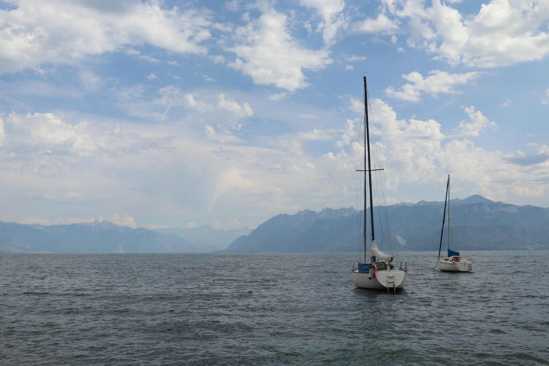 Segelboote auf dem Genfersee bei Lausanne mit den Alpen im Hintergrund
