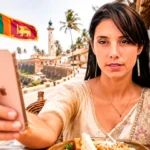 Caroline im srilankischen Kleid macht ein Selfie mit ihrem Smartphone vor dem Teezug in Sri Lanka