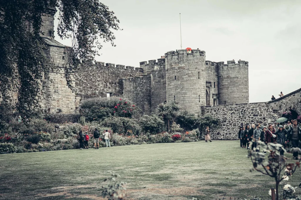 The ramparts and gardens of Stirling Castle, Scotland, with visitors walking on the lawn and among the flower beds.