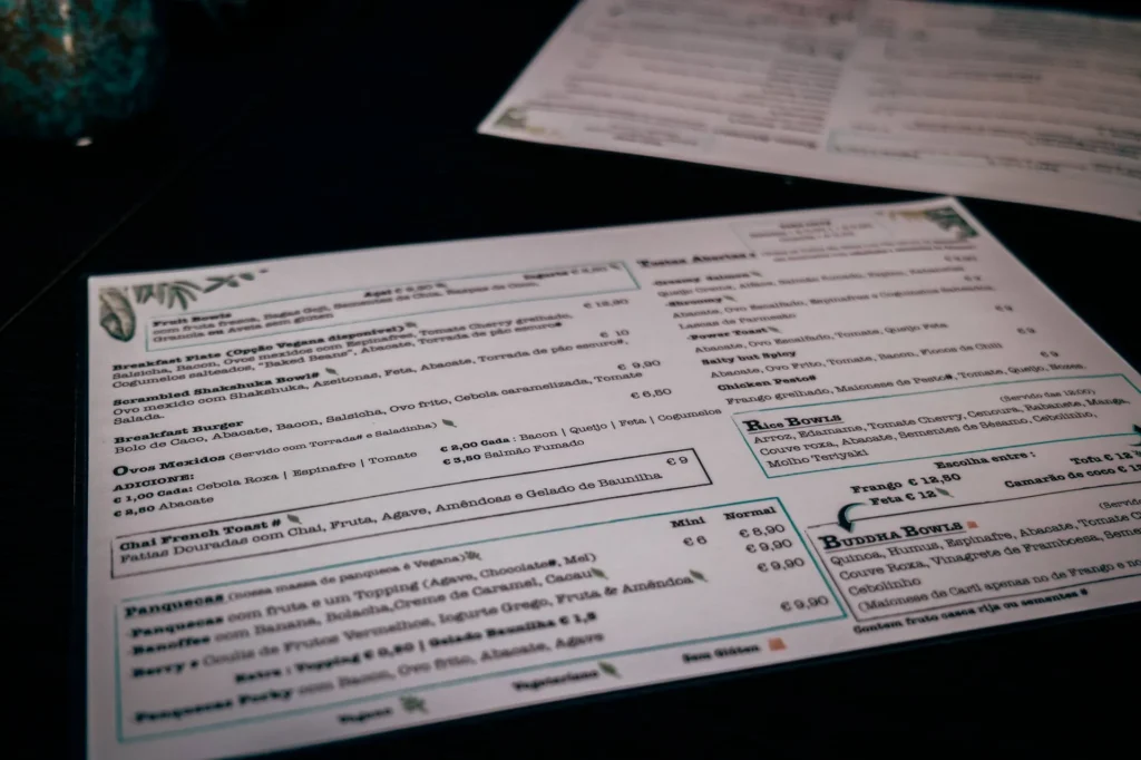 Goji restaurant menu in Lagos, Algarve, placed on a dark table, with dishes and drinks visible in Portuguese and English.