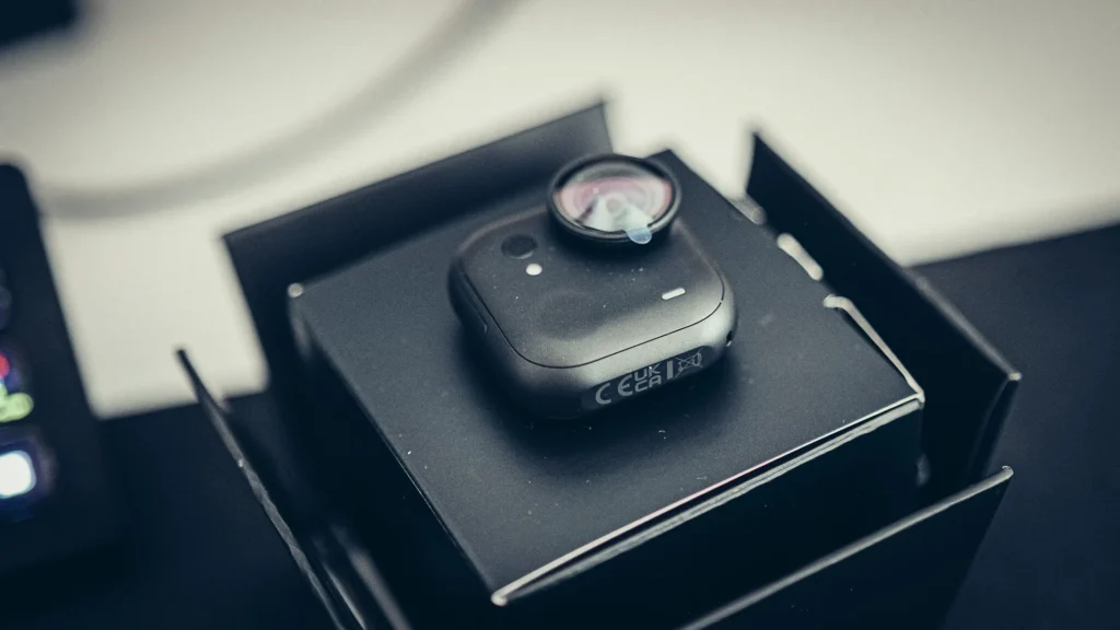 Das Kameramodul der Insta360 GO Ultra in mattem Schwarz, beim Auspacken in seiner Schale liegend, mit der Schutzfolie noch auf dem Objektiv.