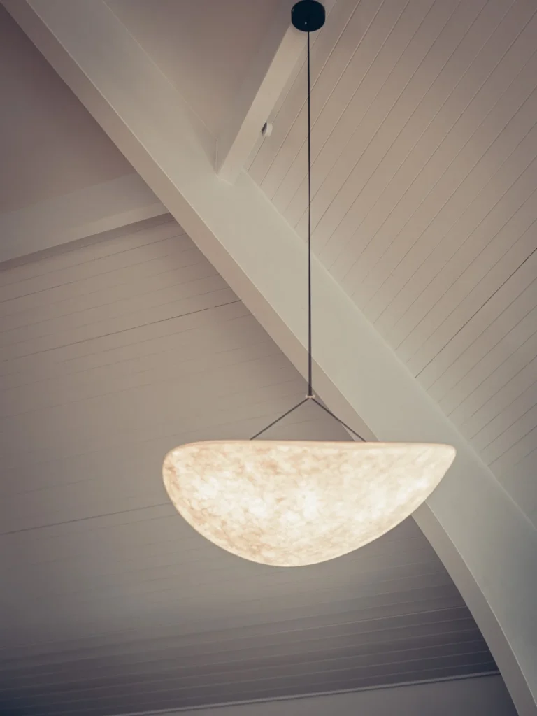 Pendant light hanging under the high white-painted timber ceiling of the Linnhe Storehouse and Cafe at Portnacroish, Argyll.