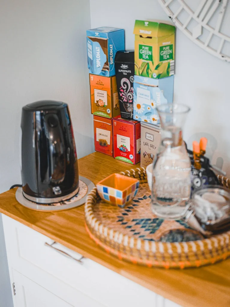 Tea corner in a holiday rental in Glencoe, Highlands, with a selection of teas, an electric kettle, and accessories on a wicker tray.