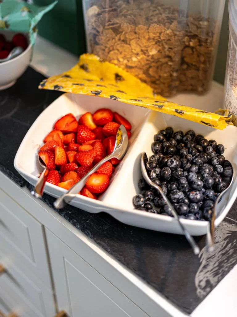 Fresh strawberries and blueberries arranged in a compartmentalized dish, with cereals in the background on a breakfast buffet at Rocklee Bnb in the Scottish Highlands during summer.