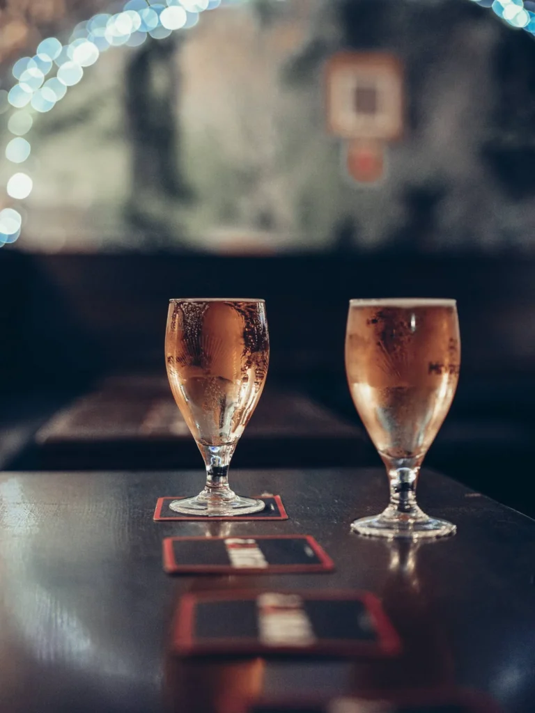 Two glasses of beer on a wooden table at the Settle Inn, in Stirling, in the dimly lit atmosphere of the pub.