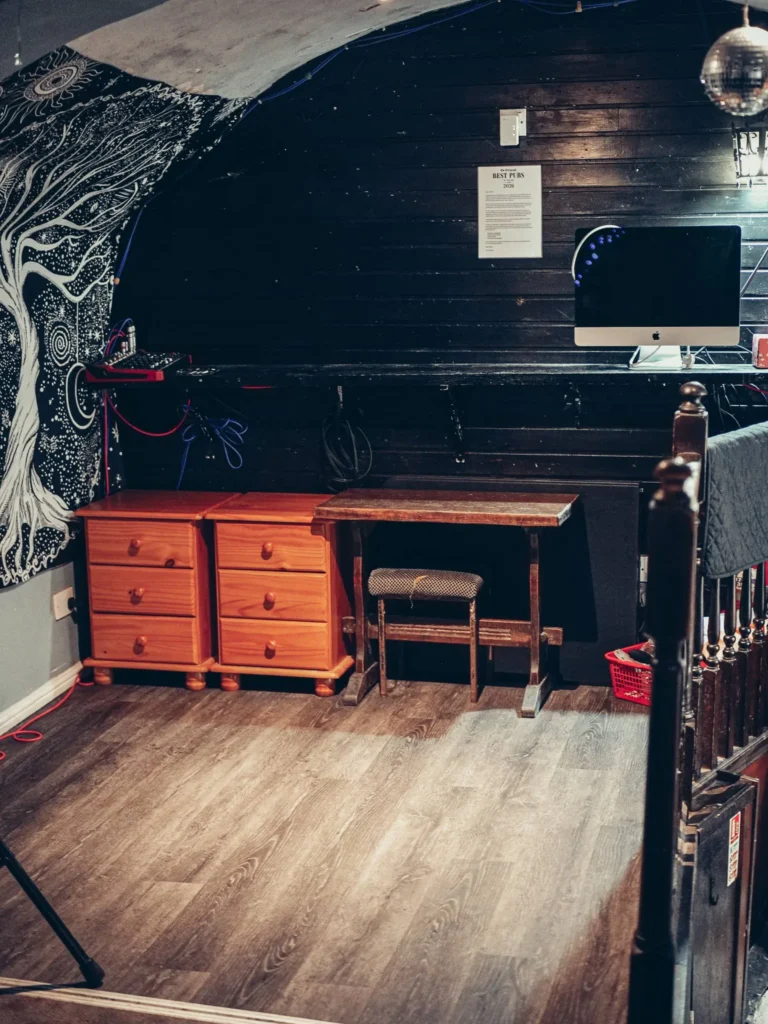 Dark corner of the Settle Inn, in Stirling: a wooden desk, a chair, and wall decor, far from the image of a modern city center pub.