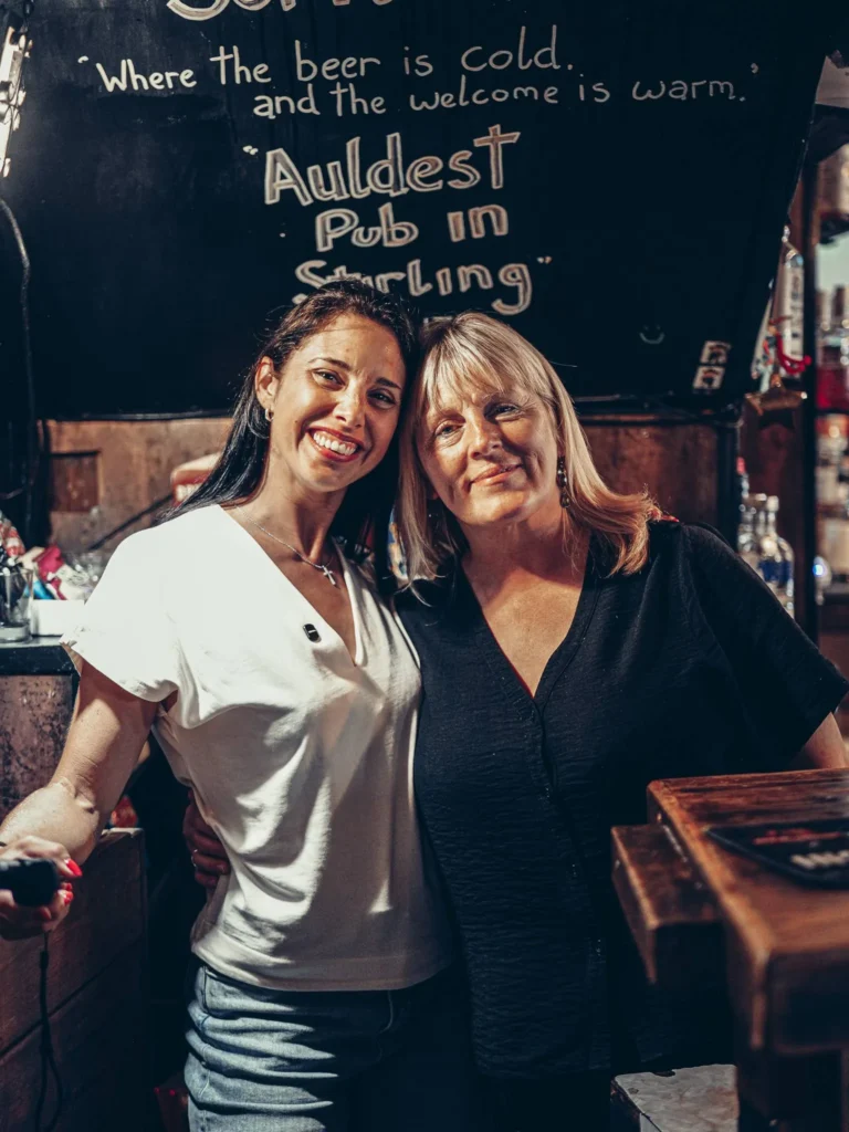 Caroline with a regular at the Settle Inn, in front of the counter, in Stirling: the welcome from the pub regulars even included a kiss.