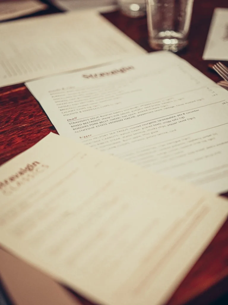 Stravaigin menus laid out on the wooden table at the start of dinner on 14 August 2026, in Glasgow.