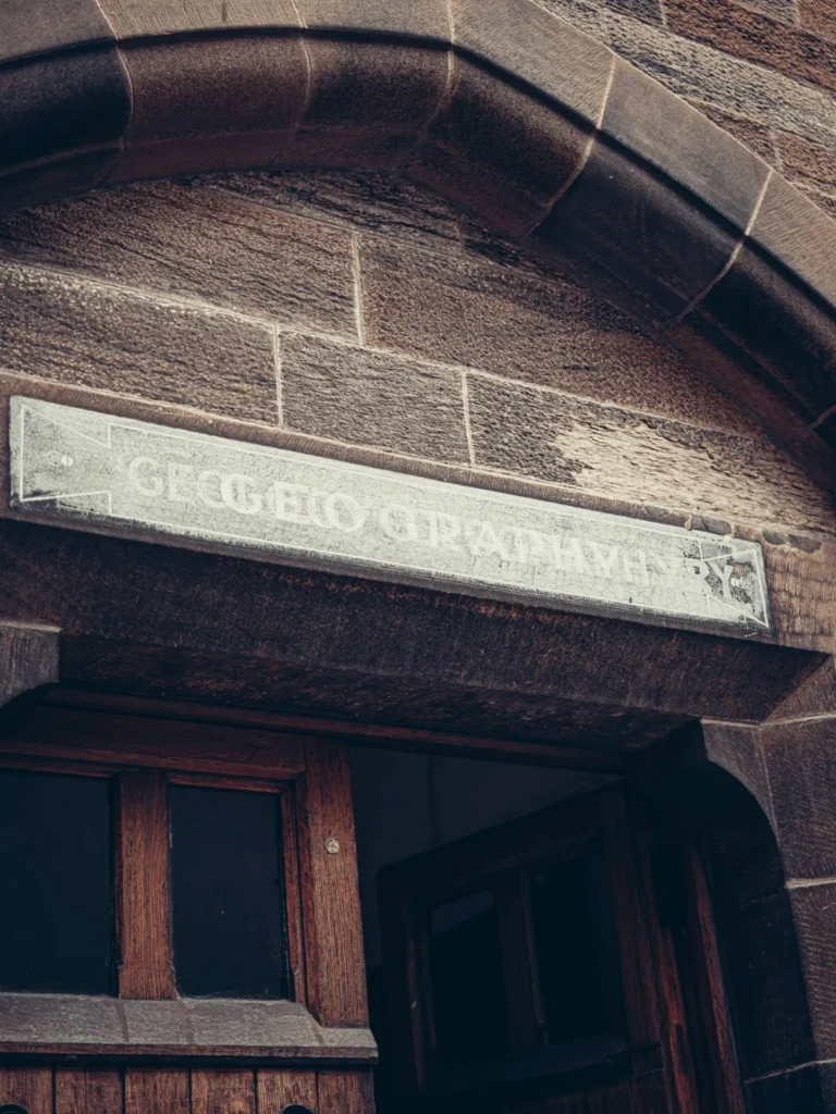 Stone and wood entrance under a neo-Gothic arch of the University of Glasgow.