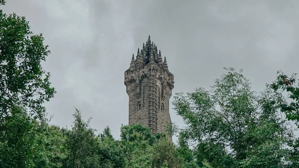 The Wallace Monument rises above the Abbey Craig forest under a cloudy sky, Stirling, Scotland