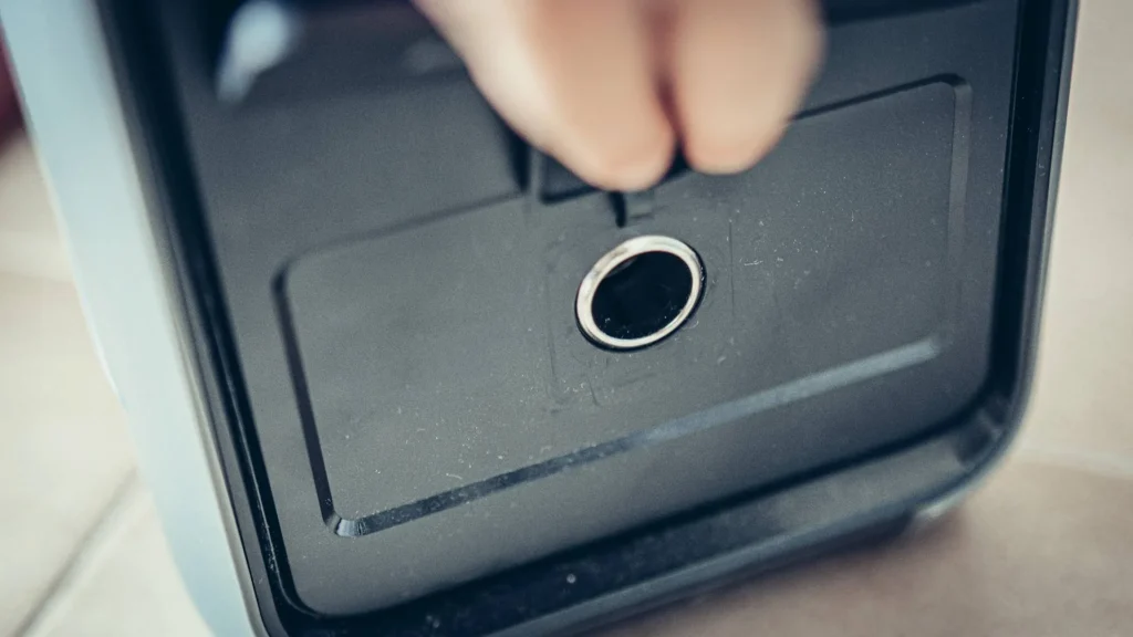 Close-up of a circular port of the ALLPOWERS P1800 electric station, with a hand manipulating the access hatch.