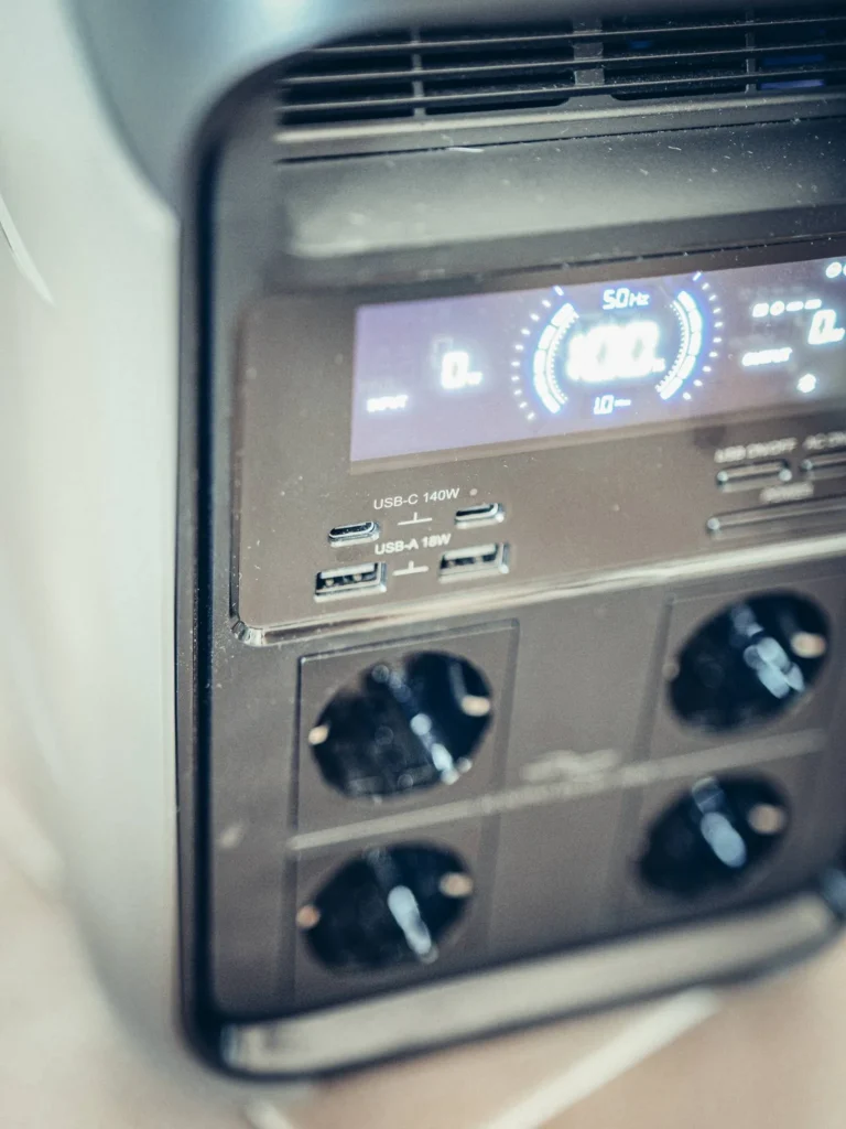 Close-up of the ALLPOWERS P1800 power station, integrated control screen on, showing the front ports: two USB-C (140 W), two USB-A (18 W), and four AC outlets. The display provides charging and usage information.