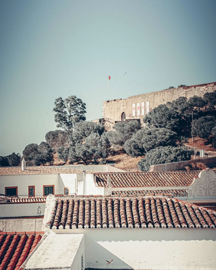 View of the red-tiled roofs and the castle of Castro Marim under a clear sky, with Mediterranean trees in the background. Summer atmosphere in the Algarve, Portugal, on May 18, 2023.