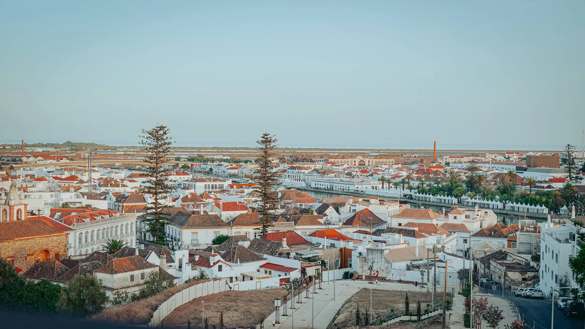 View from the terrace of the Nomad, rooftop of Maria Nova in Tavira, over the rooftops of the city and the Ria Formosa that opens towards the ocean at the end of the day.