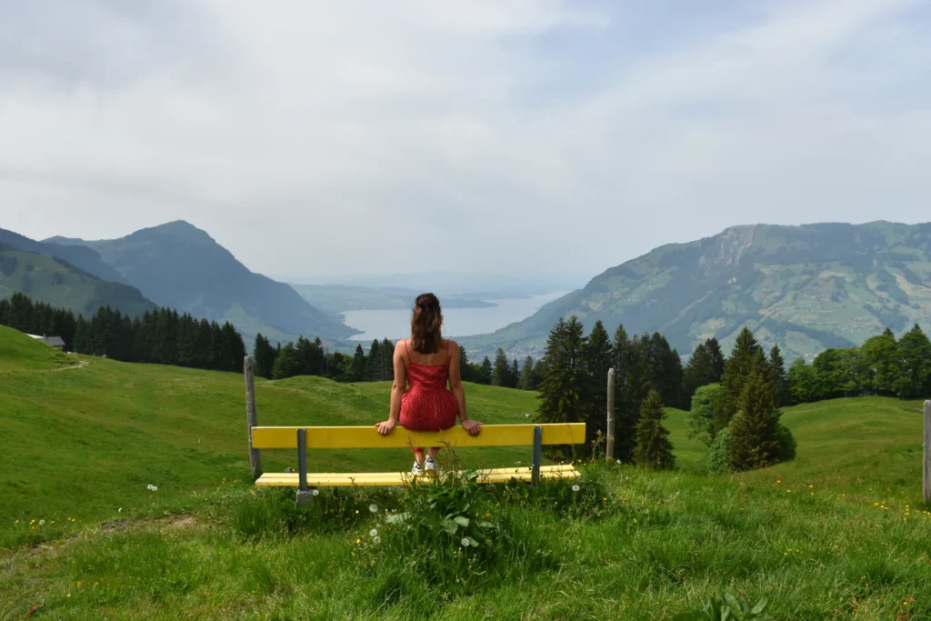 Caroline auf einer gelben Bank oberhalb des Vierwaldstättersees im Gebiet Urmiberg