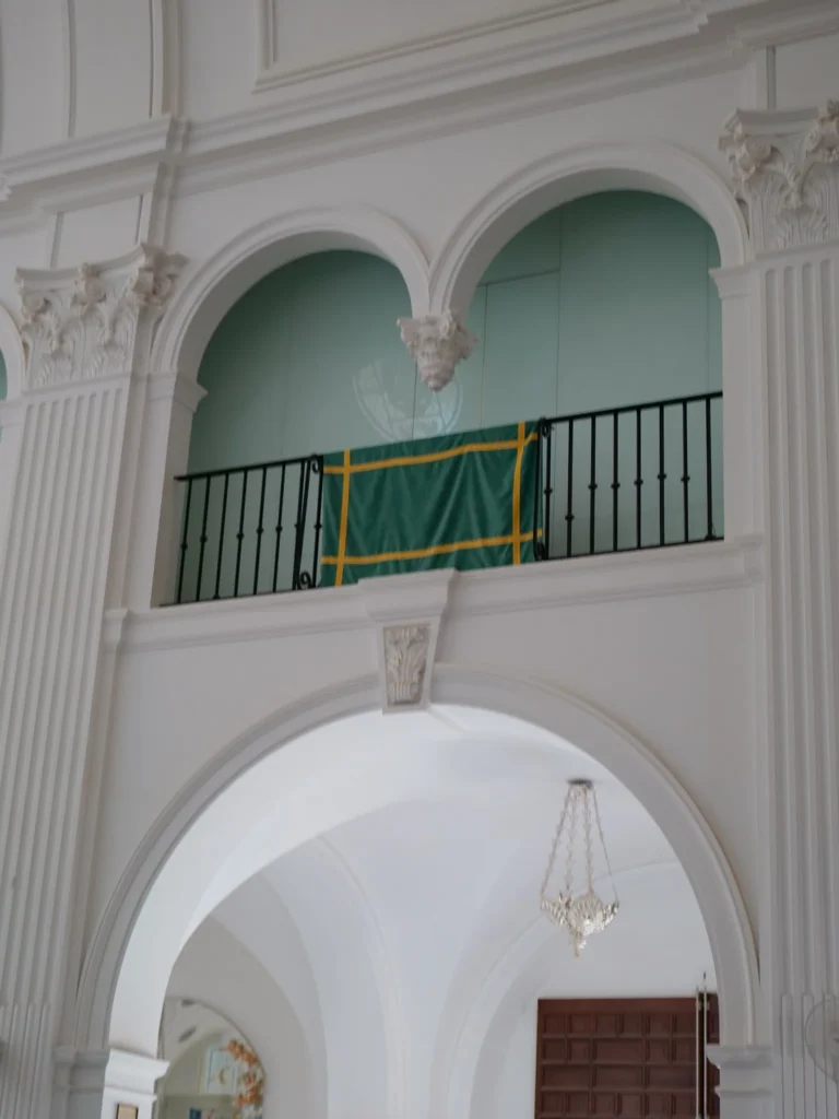Grüne Tenture mit gelben Borten über einer Emporenbrüstung in der Wallfahrtskirche von El Rocío