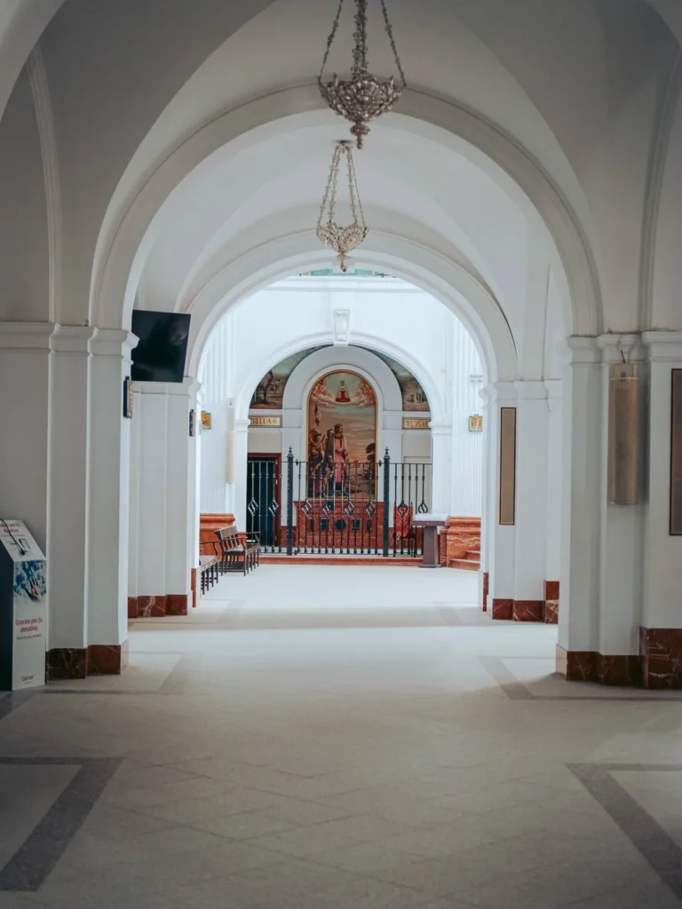 Weiße Bögen und Hängeleuchten in einem Seitenschiff der Wallfahrtskirche von El Rocío